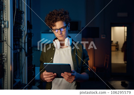 Teenager guy IT technician working on tablet in server room 106295579