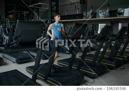 Teenager boy running exercising on treadmill machine at sports gym 106295586