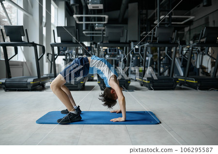 Teenager boy doing gymnastics exercise standing in bridge position 106295587