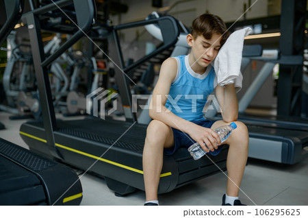 Preteen boy rest after hard training workout on treadmill at gym 106295625