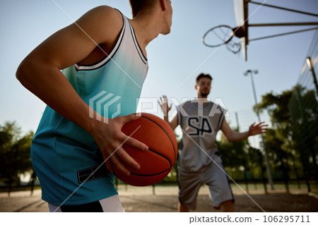Closeup teenager son preparing to throw ball into basket hoop Closeup teenager son preparing to throw ball into basket hoop 106295711