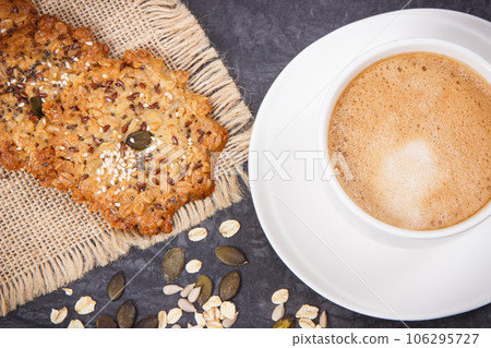 Cup of coffee with milk and fresh baked oatmeal cookies with honey and healthy seeds 106295727