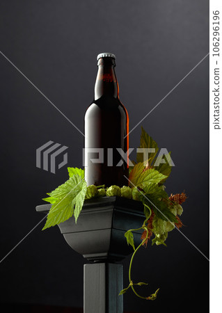 Beer with green hops and wheat ears on a black podium. Beer with green hops and wheat ears on a black podium. 106296196