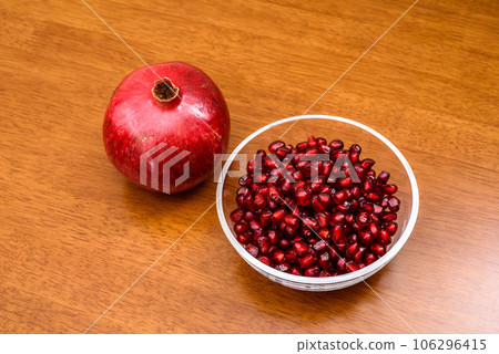 Pomegranate fruits and pomegranate seed coats filled in a bowl Image of wood grain table 106296415