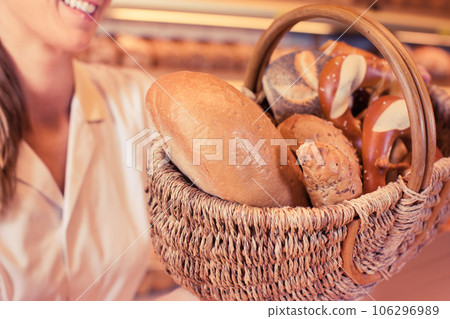 sales woman in bakery with basket of bread and rolls 106296989