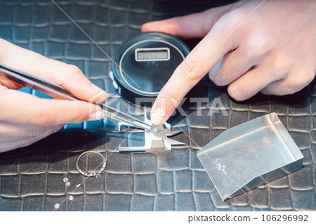 Close-up of jeweler sorting diamonds on her workbench 106296992