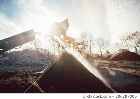 Heavy machinery moving earth and biomass in compost works 106297000