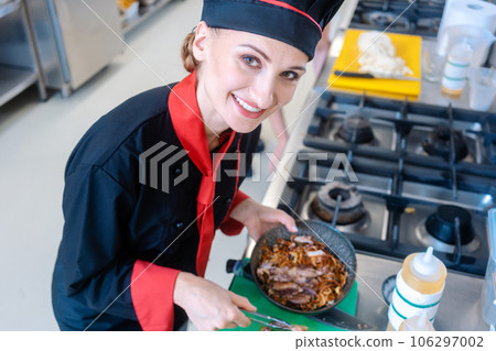 Chef stirring pasta in restaurant kitchen 106297002