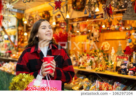 Happy girl with paper cup of coffee walking in Christmas fair Happy girl with paper cup of coffee walking in Christmas fair 106297104