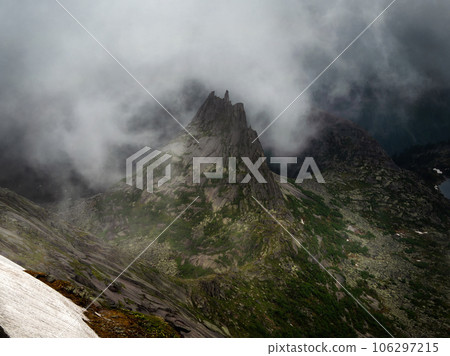 Impressive pointed peak with jagged edges in dense frightening thunderclouds, bad weather in the mountains, difficult trekking. Lost world in the mountains. 106297215