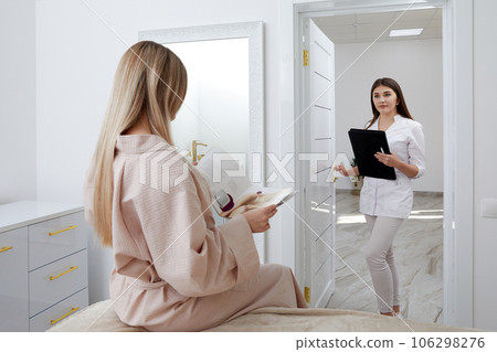 Young female cosmetologist confidently enters treatment room with waiting patient Young female cosmetologist confidently enters treatment room with waiting patient 106298276