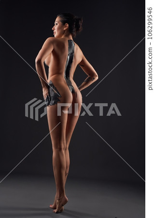 Naked woman with black body paint standing in studio Naked woman with black body paint standing in studio 106299546