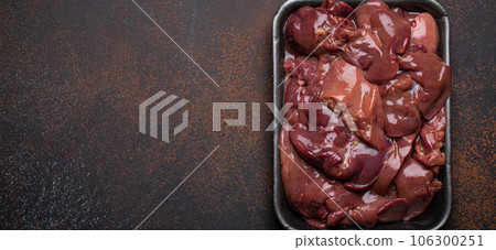 Raw chicken liver in black supermarket tray top view on dark rustic concrete background kitchen table. Healthy food ingredient, source of iron, folate, vitamins, minerals. Space for text Raw chicken liver in black supermarket tray top view on dark rustic concrete background kitchen table. Healthy food ingredient, source of iron, folate, vitamins, minerals. Space for text 106300251
