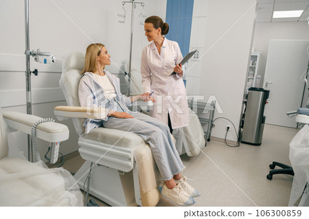 Nurse or doctor talking with patient while preparing her for infusion drip in hospital  106300859