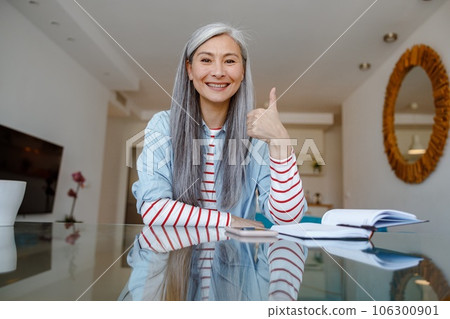 Joyful woman doing thumbs up gesture at home 106300901