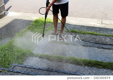 A high-pressure washer cleaning the gravel-filled concrete approach to the entrance General cleaning 106300974