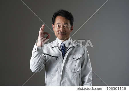 Middle-aged worker giving an OK sign Black background Middle-aged worker giving an OK sign Black background 106301116
