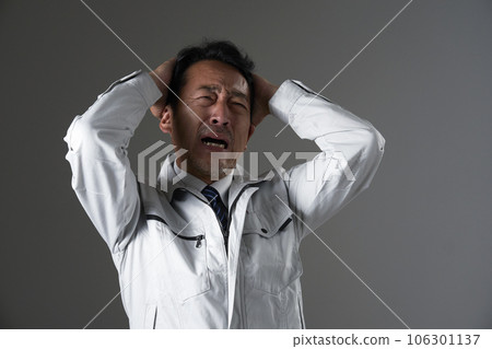 Middle-aged worker holding his head black background 106301137