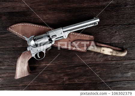 Old west weapon. Colt Revolver and knife with holster on deck. 106302379