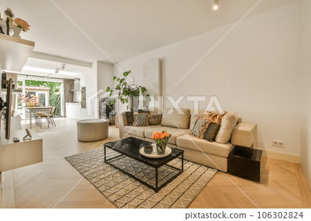 a living room with white walls and hardwood flooring, including a large coffee table in the center of the room 106302824