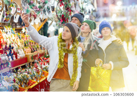 Friendly family chooses Christmas souvenirs and toys Friendly family chooses Christmas souvenirs and toys 106303600