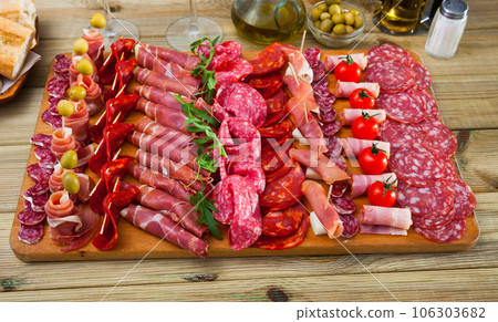 Slicing sausages fuet, ham, salami, chorizo with cherry tomatoes and olives 106303682