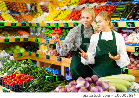 Grocery store employee points hand to young trainee girl Grocery store employee points hand to young trainee girl 106303684