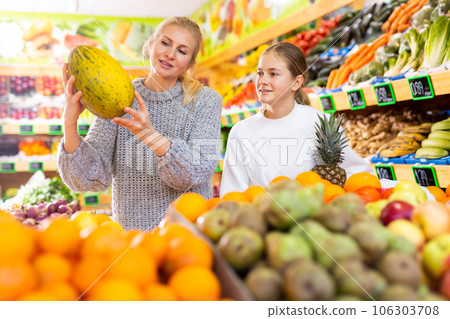 Friendly teenage girl and her mother shopping in fruit store 106303708