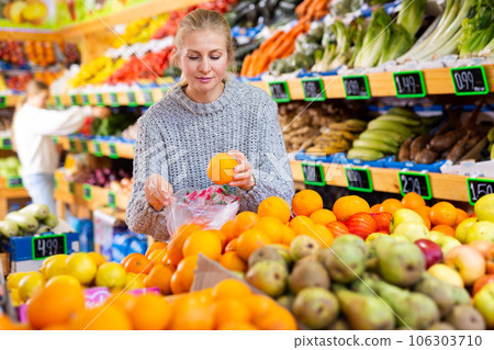 Smiling woman choosing sweet ripe oranges in farmer store 106303710