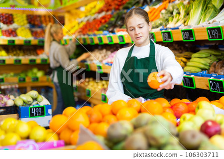Focused young girl working at family fruit and vegetable shop 106303711