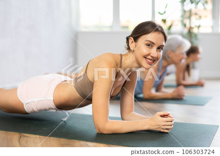 Women of different generations yoga showing plank pose in wellness center 106303724