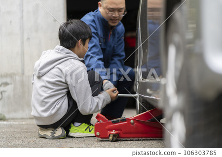 A man who changes a car tire and a child who helps A man who changes a car tire and a child who helps 106303785