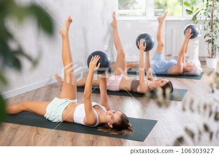 Teenage girl doing pilates with soft ball in group Teenage girl doing pilates with soft ball in group 106303927