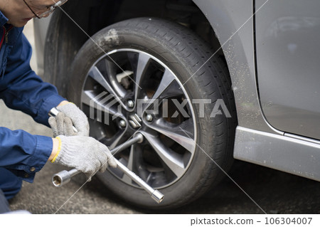 A man changing a tire of a light car A man changing a tire of a light car 106304007