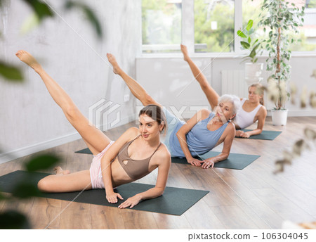 Young woman doing side-lying leg raise in yoga studio Young woman doing side-lying leg raise in yoga studio 106304045