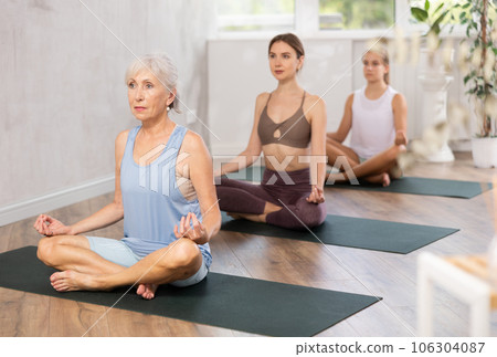 Women three generations practise yoga, meditation in lotus position in fitness studio 106304087