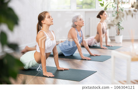 Teenage girl doing Urdhva Mukha Shvanasana during group yoga workout 106304121