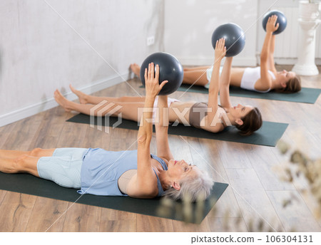 Elderly woman exercising with ball during group workout 106304131