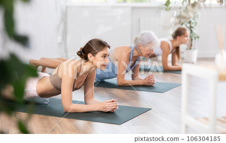 Young woman holding plank pose on forearms in fitness studio 106304185