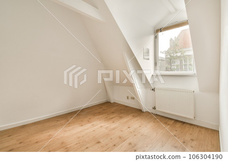 an empty room with wood floor and white walls, there is a window in the corner that looks out onto the street 106304190
