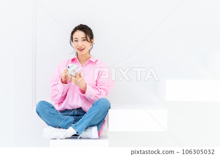 Young woman looking at smartphone on stairs 106305032