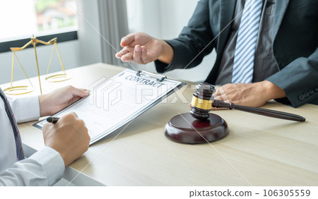 Lawyer hand holding pen and providing legal consult business dispute service at the office with justice scale and gavel hammer 106305559