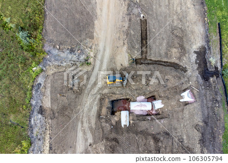 Dozer next to an open trench with two culverts ready for a connection juncture.  106305794