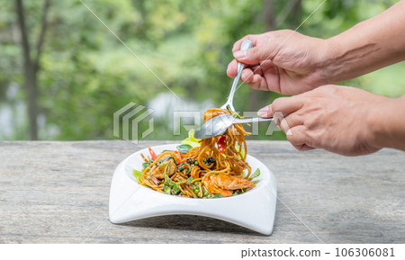 Hand scooped spaghetti with shrimp stir-fried with herbs. Local Thai food on a white plate Hand scooped spaghetti with shrimp stir-fried with herbs. Local Thai food on a white plate 106306081