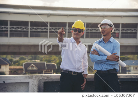 Two men engineer look at blueprint architecture building contractor design in modern city development. Males engineer holding project planing partner teamwork. Man meeting together construction site 106307307