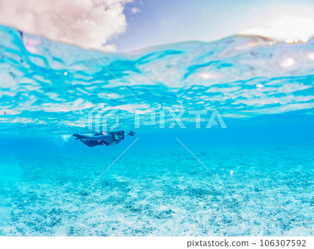 Half-surface photography of a diver swimming on a beautiful white sand beach (Ama Beach, Zamami Island, Kerama Islands, Shimajiri-gun, Okinawa Prefecture) 106307592