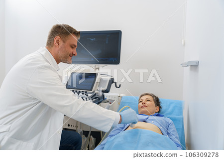 Male sonographer doing abdominal ultrasound scanning for patient in medical clinic 106309278
