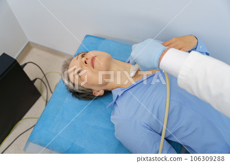 Middle aged woman patient during ultrasound examination of thyroid lying on couch in medical office Middle aged woman patient during ultrasound examination of thyroid lying on couch in medical office 106309288