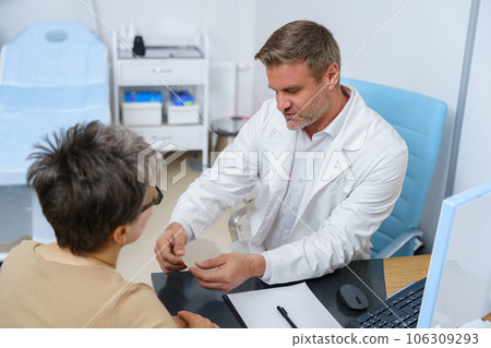 Plastic surgeon shows female patient breast implant samples for her future surgery in clinic Plastic surgeon shows female patient breast implant samples for her future surgery in clinic 106309293