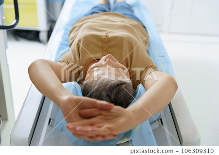 Female patient lying on table and entering CT machine during examination procedure in hospital 106309310